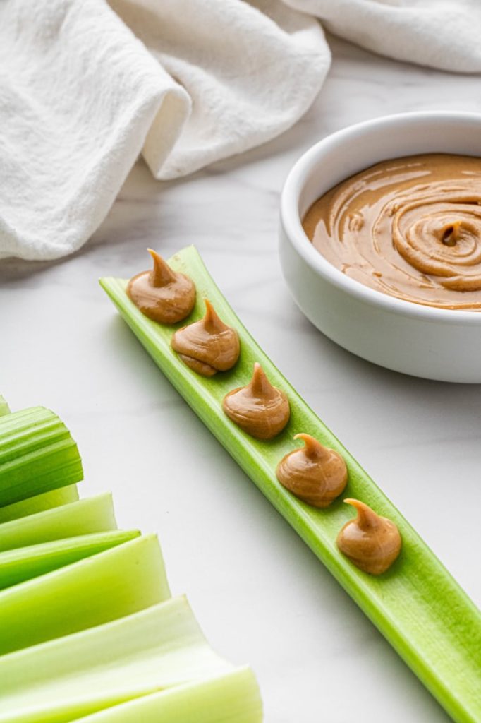 Celery sticks with peanut butter on white plate