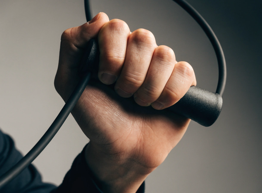 Close-up of a hand gripping a resistance band handle with controlled tension, illustrating joint-friendly movement during home strength training