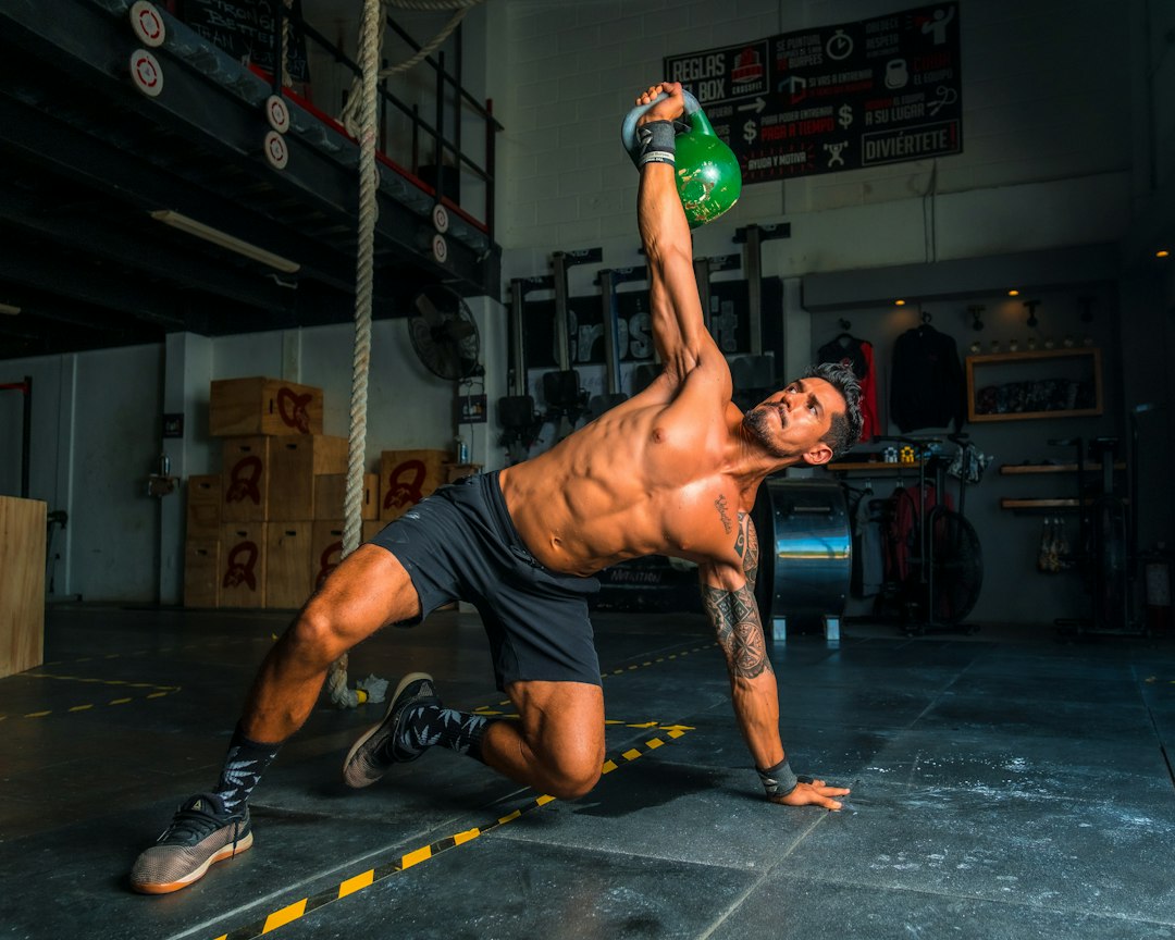 Athlete performing light bodyweight active recovery mobility work on a mat in a home gym setting