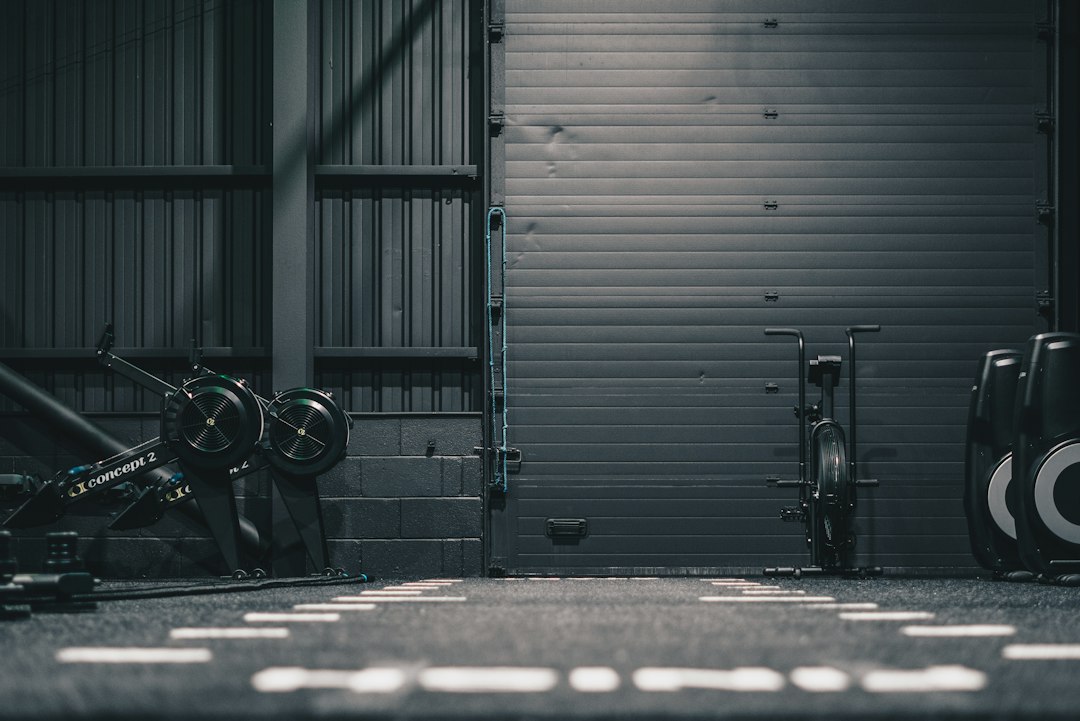Compact single car garage gym setup with folding wall rack and rubber flooring