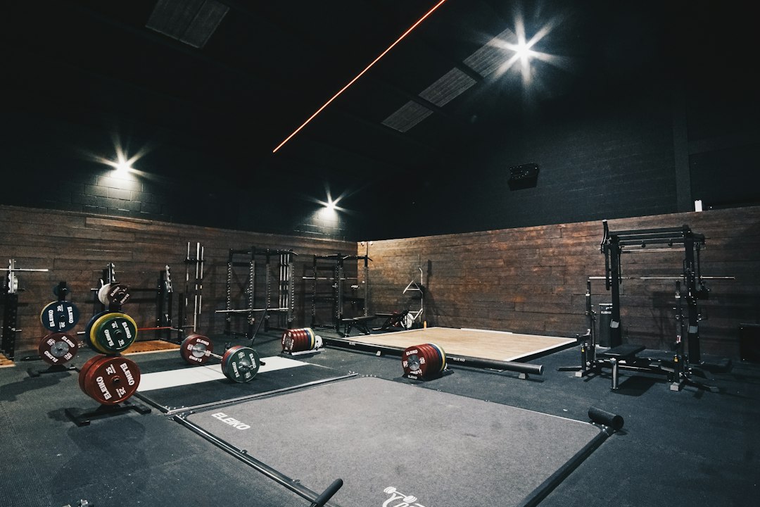 Custom garage gym deadlift platform with plywood base and dense rubber mats holding a barbell.